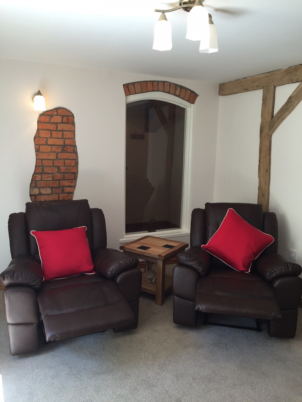 Leather recliners next to open brick feature and wooden beam